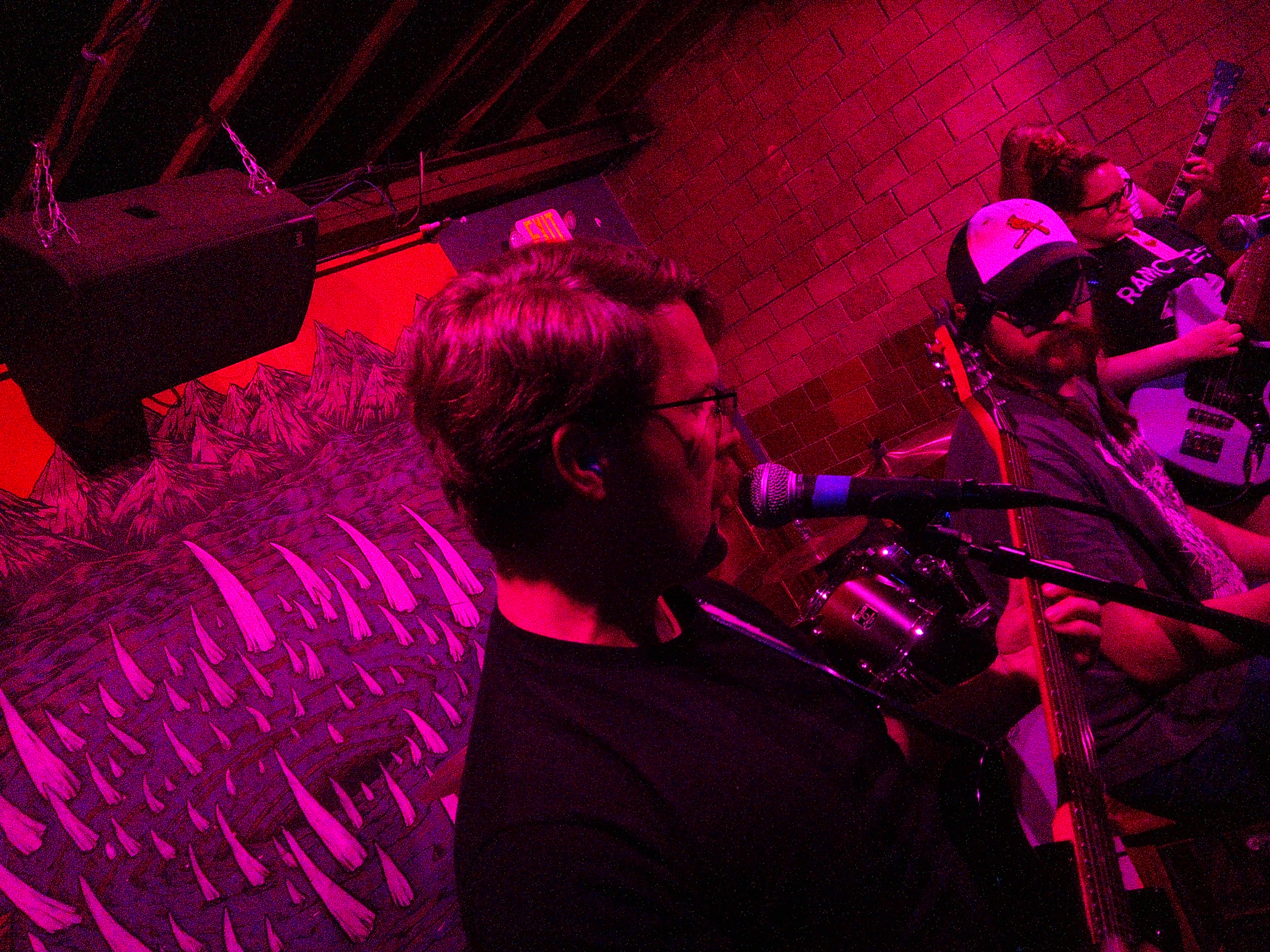 David centered in the frame singing and playing guitar with Ray to his right